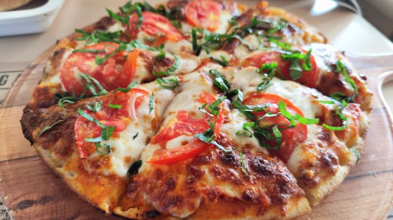Close-up of a fresh Margherita pizza with tomatoes and basil. Perfect for Italian cuisine promotions. - Photo by Sonali Mehta on Pexels
