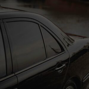 Close-up of a black car's side view with tinted windows by a calm riverbank. - Photo by Rahib Hamidov on Pexels