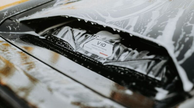 Detailed image of a sleek car being washed with foam, showcasing the car's design and cleanliness. - Photo by Luke Miller on Pexels