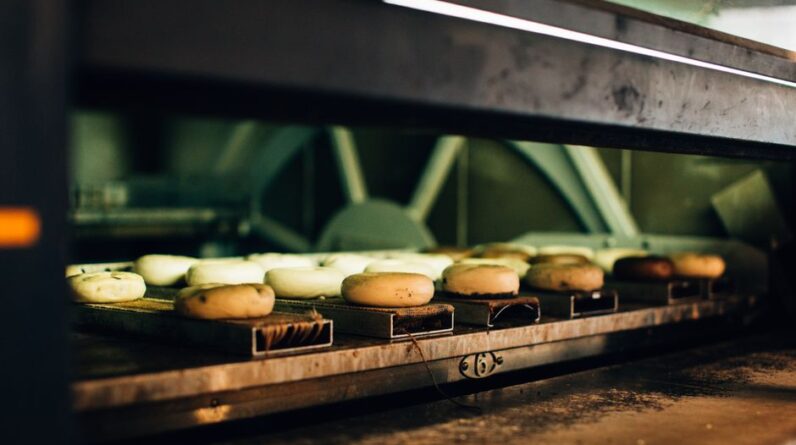 Multiple bagels baking in an industrial oven, showcasing a warm bakery ambiance. - Photo by Rachel Claire on Pexels