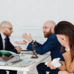 A lawyer mediates an emotional settlement discussion with a distressed couple in a legal office. - Photo by https://kaboompics.com/ on Pexels