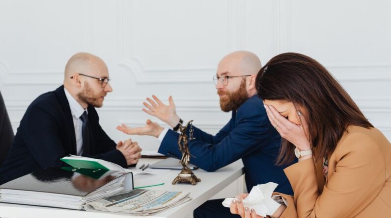 A lawyer mediates an emotional settlement discussion with a distressed couple in a legal office. - Photo by https://kaboompics.com/ on Pexels
